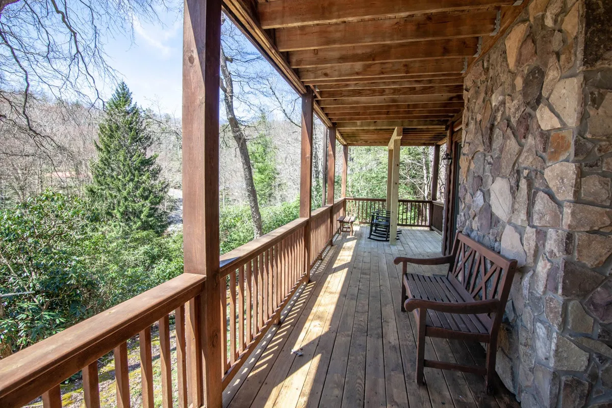 A bench rests beside a wooden railing and stone wall, surrounded by greenery, offering a secluded spot to relax and enjoy nature. The composition hints at moments of wildlife observation and peaceful stargazing, enhancing the connection with the mountain environment.