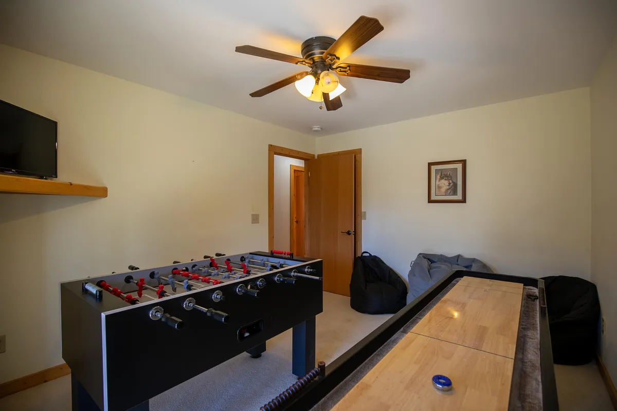 The image captures another angle of the game room, highlighting the foosball and shuffleboard tables, bean bags for lounging, wall art, and an overall playful, relaxed atmosphere.